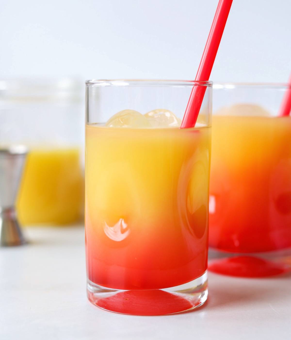 Vodka sunrise in a small cocktail glass with red straw.
