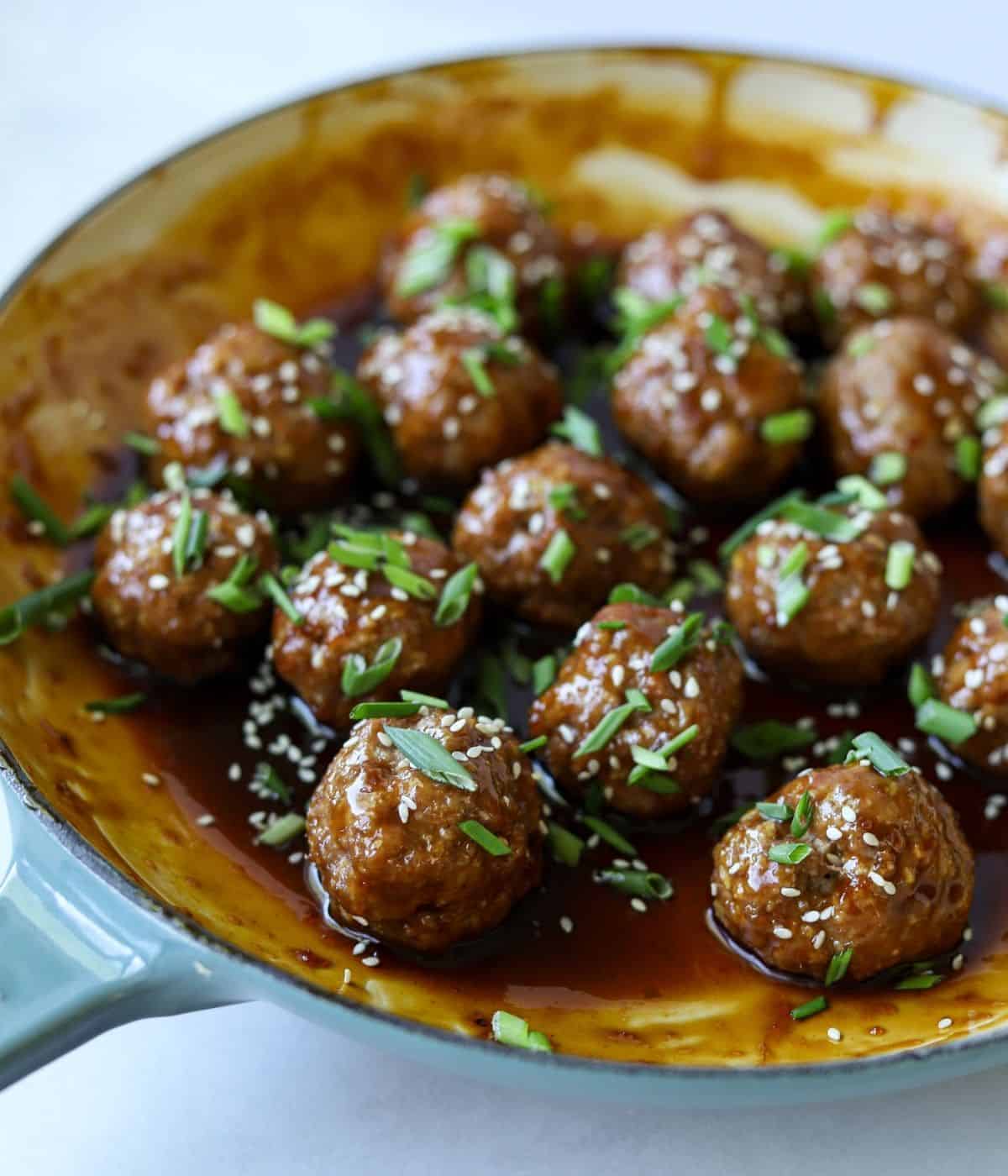 Asian meatballs in enamel pan tossed in glaze.