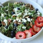 white bowl full of strawberry and pecan salad topped with feta