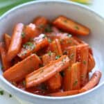 brown sugar honey glazed carrots in stoneware bowl topped with parsley