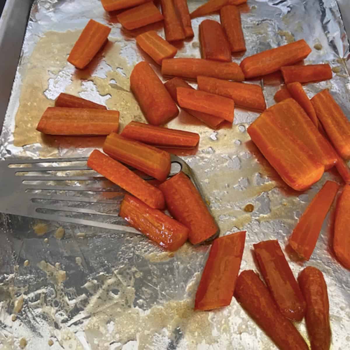spatula flipping carrots over on cookie sheet