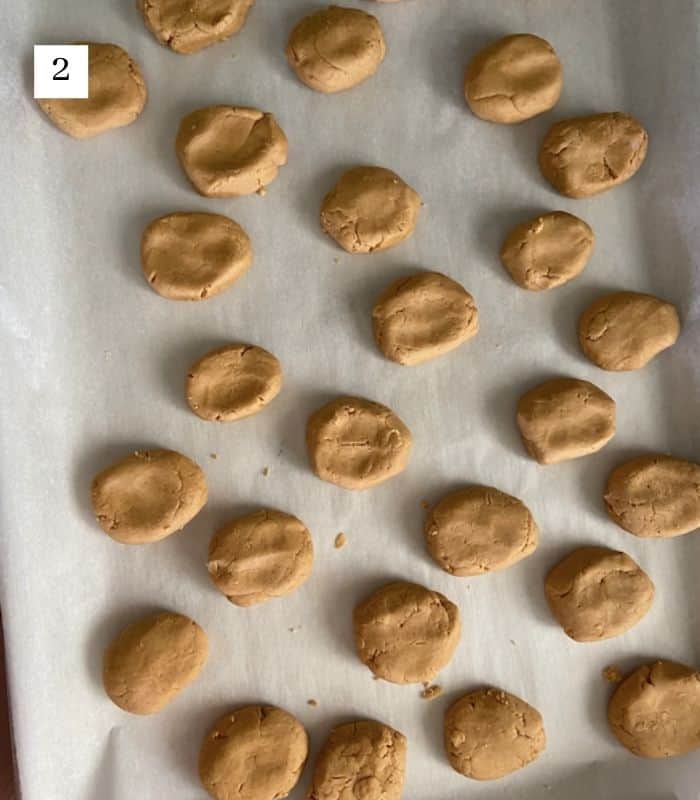 peanut butter filling rolled into eggs on parchment paper lined cookie sheet