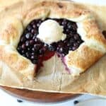close up view of blueberry galette with one missing slice and topped with scoop of vanilla ice cream