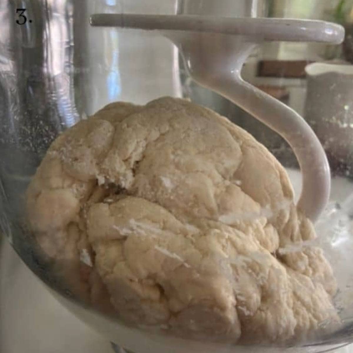 Pizza dough in stand mixer with dough hook attachment.