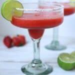 close up view of frozen strawberry margarita topped with lime wedge
