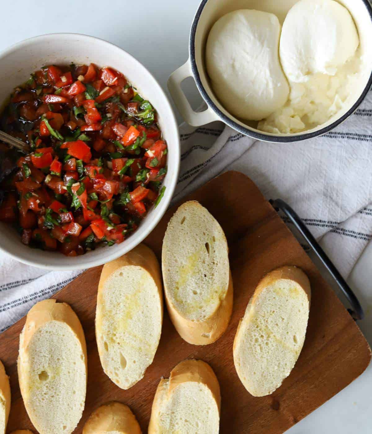 Bruschetta, french bread and burrata on serving dishes.
