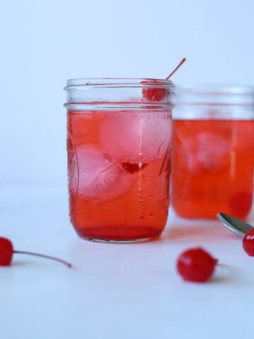 dirty shirley cocktails in glass mason jars filled with ice and topped with cherry