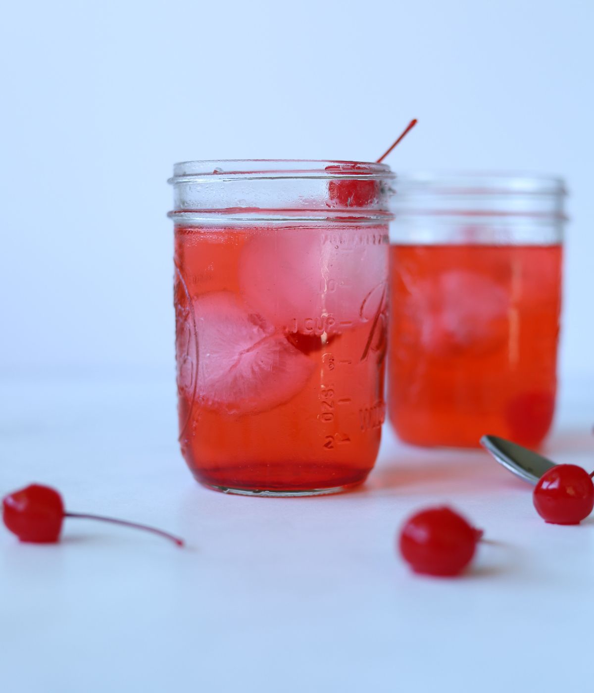 dirty shirley cocktails in glass mason jars filled with ice and topped with cherry
