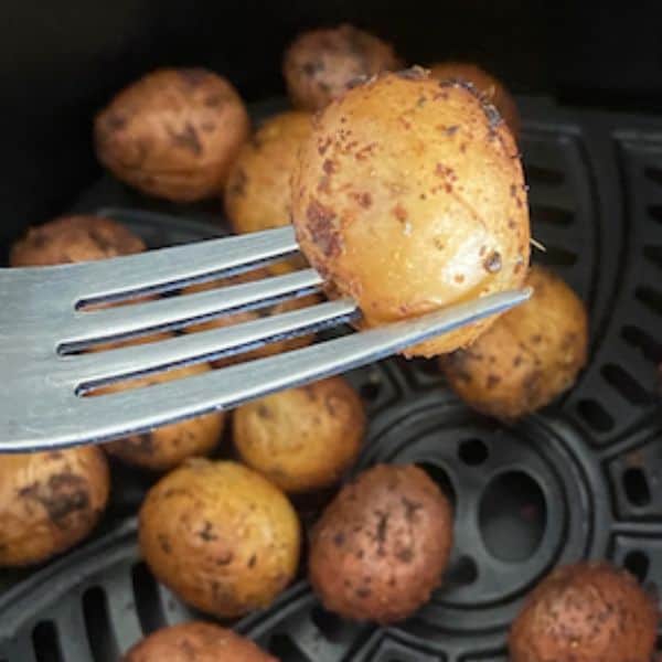 potato being stuck with a fork after air frying to check for tenderness