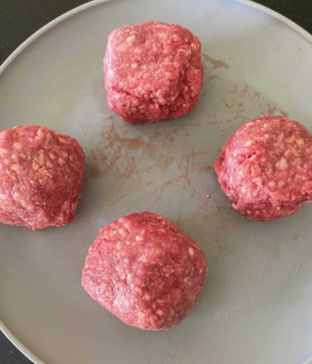Raw Ground beef balls for Smashburgers on plate. 