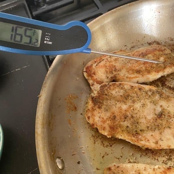 chicken sautéing in pan with instant read thermometer showing 165 degrees