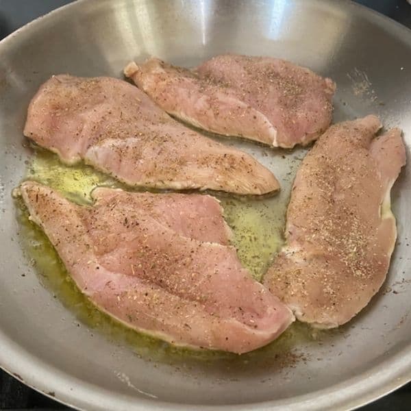 chicken sautéing on first side in stainless pan
