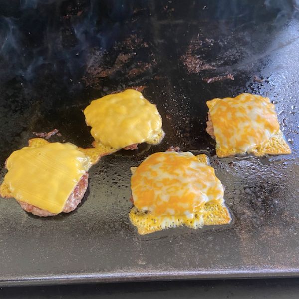 cheese melting on smash burgers on the blackstone