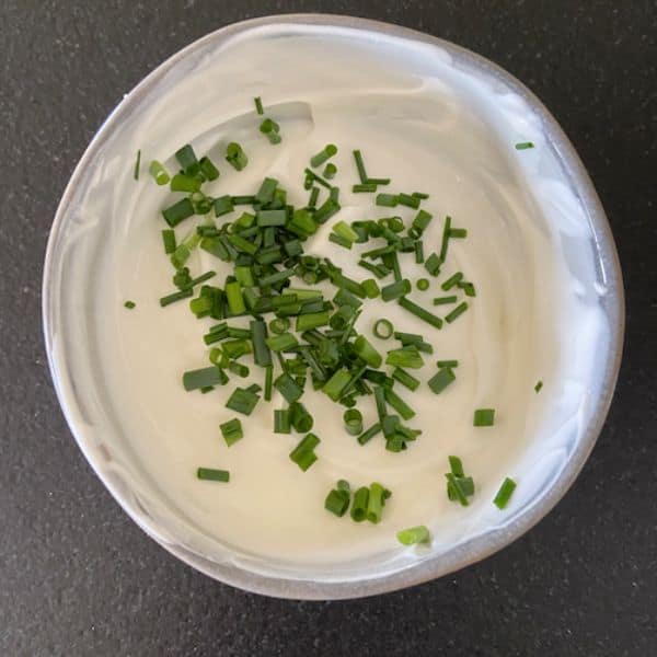 sour cream dip covered with chives in gray bowl