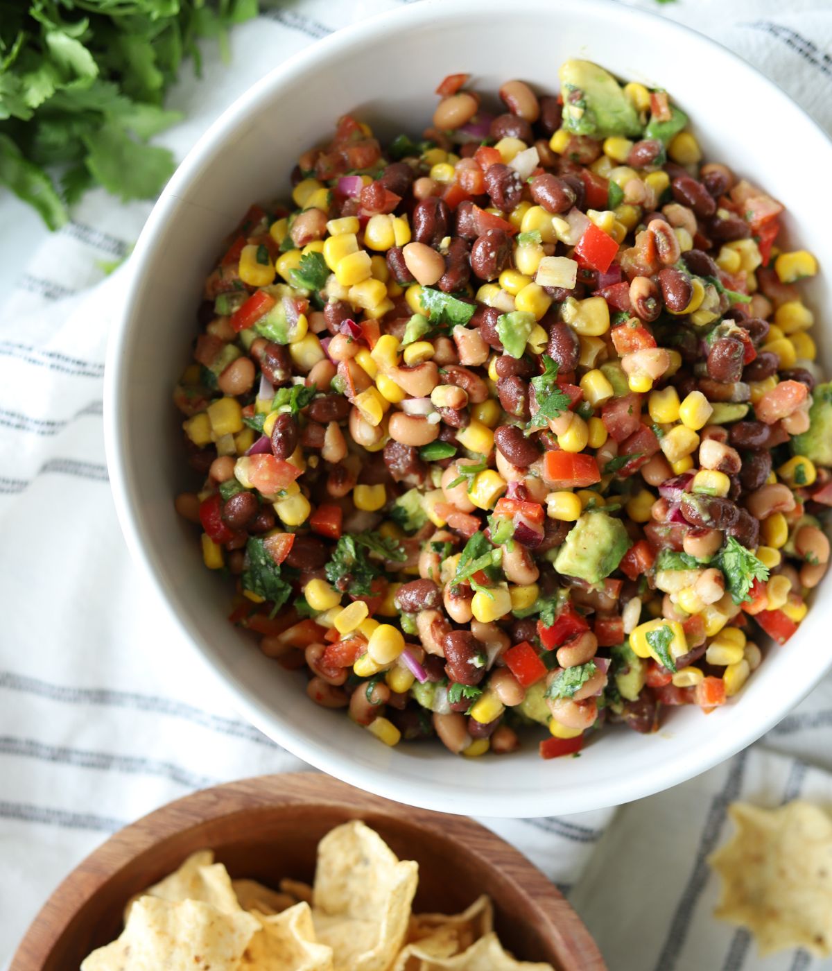 large white bowl full of cowboy caviar with a side of tostito chips