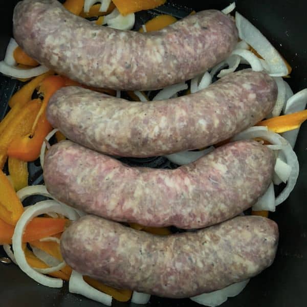 sausages on top of peppers and onions in air fryer