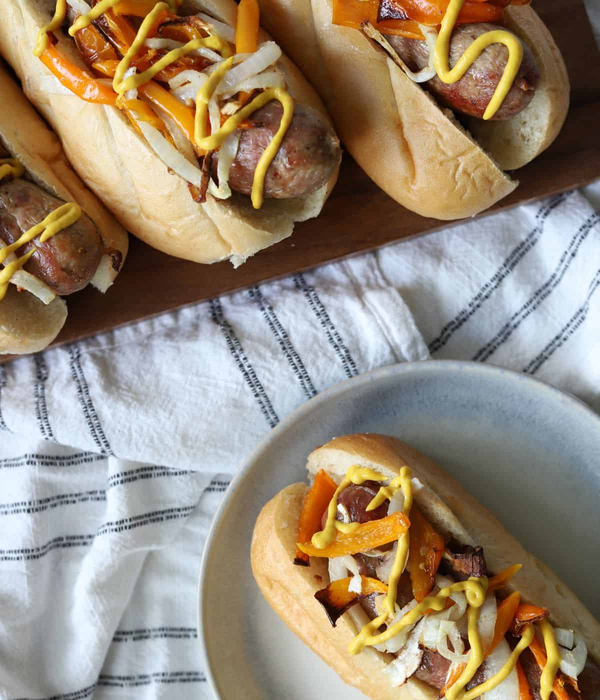 overhead view of italian sausages topped with peppers, onions, and mustard