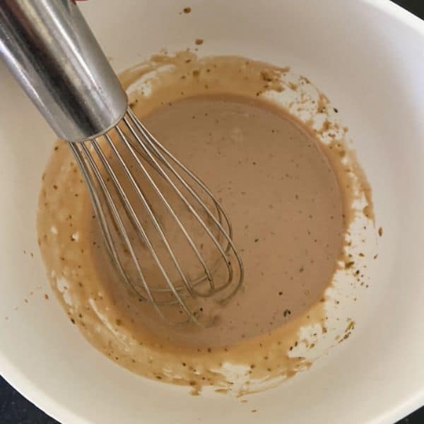 salad dressing in white bowl with whisk