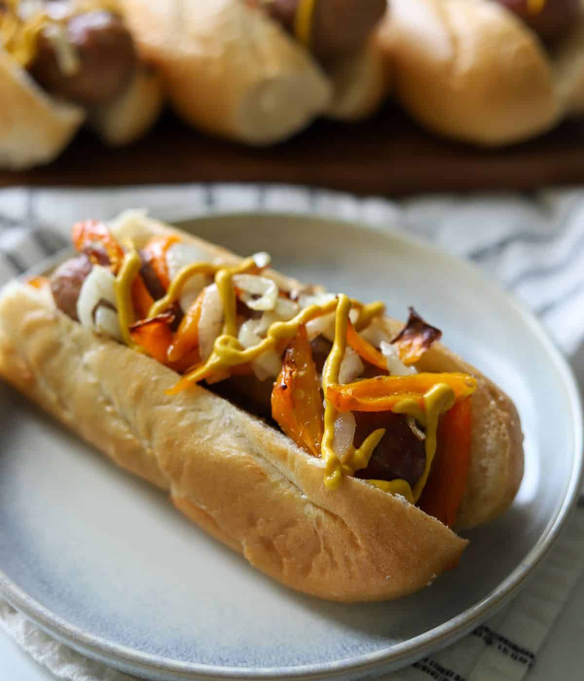 italian sausage on a plate topped with peppers and onions and mustard