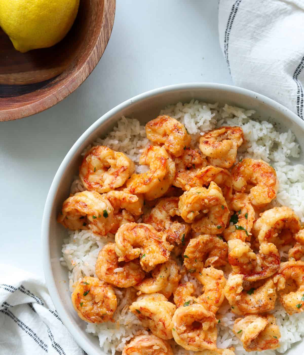 overhead view of shrimp in large bowl over rice with lemons in a bowl on side