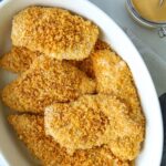 panko crusted chicken in casserole dish with side of honey mustard