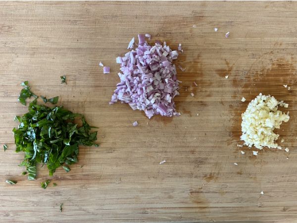 chopped basil, shallot, and garlic on cutting board