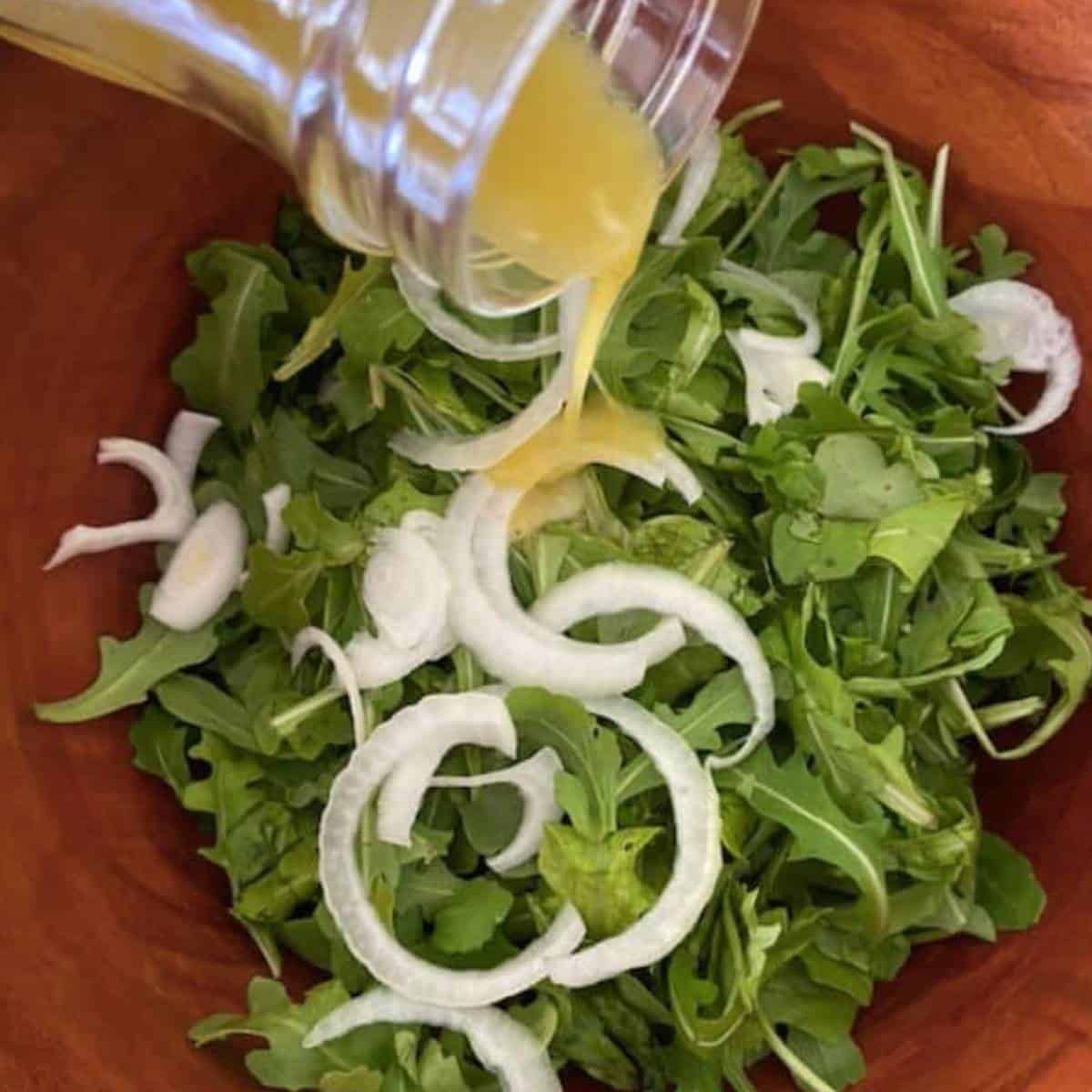Pouring dressing over salad.