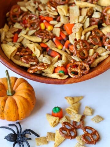 halloween snack mix in wooden bowl with a pumpkin and spider on the side