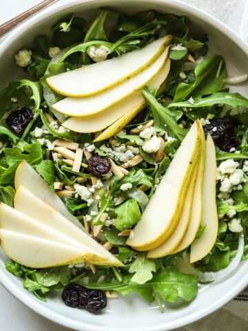overhead view of rocket and pear salad in white bowl