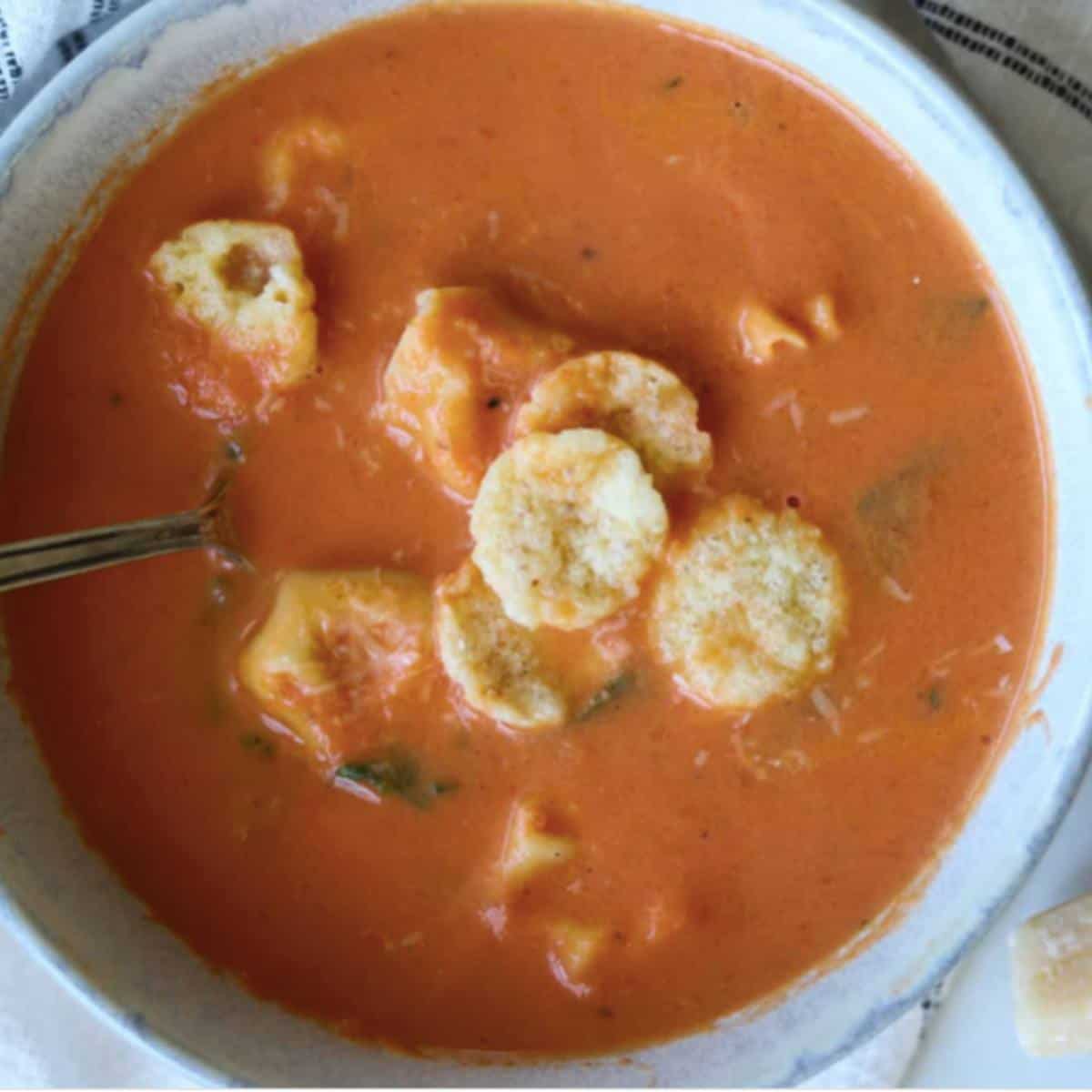 Tortellini tomato soup in bowl topped with parmesan crisps.