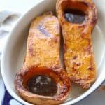 halved butternut squash in casserole dish filled with brown sugar butter mixture