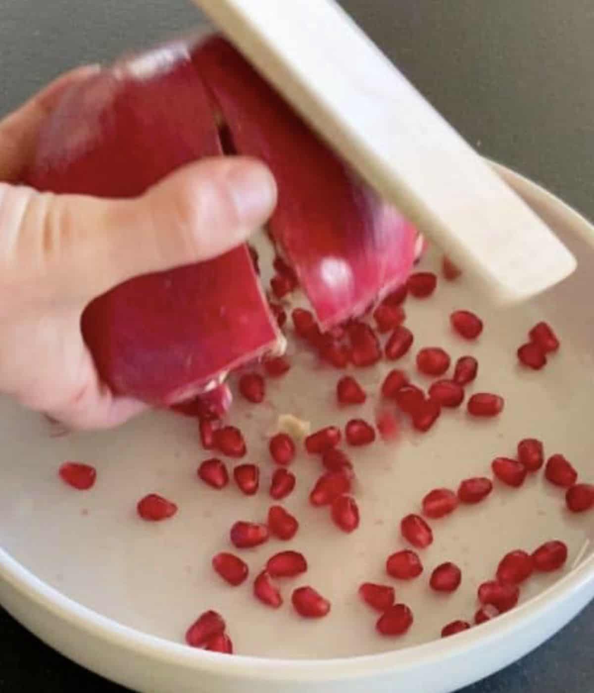 Wooden spoon hitting pomegranate.