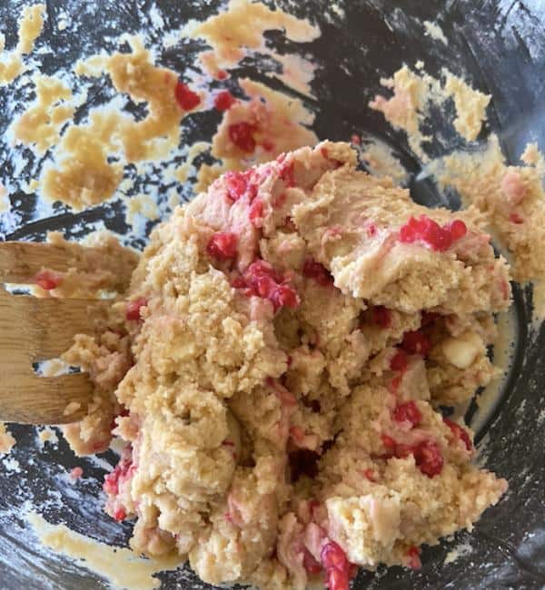 white chocolate raspberry cookie dough in glass bowl with wooden spoon