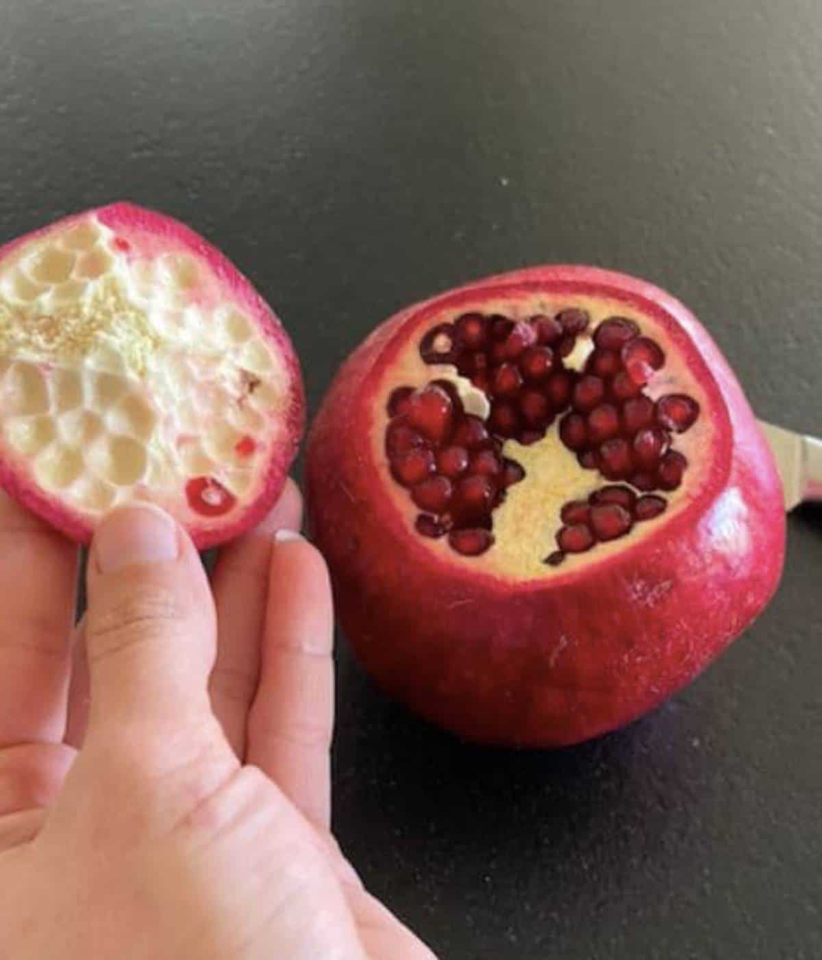 Hand holding top lid of pomegranate.