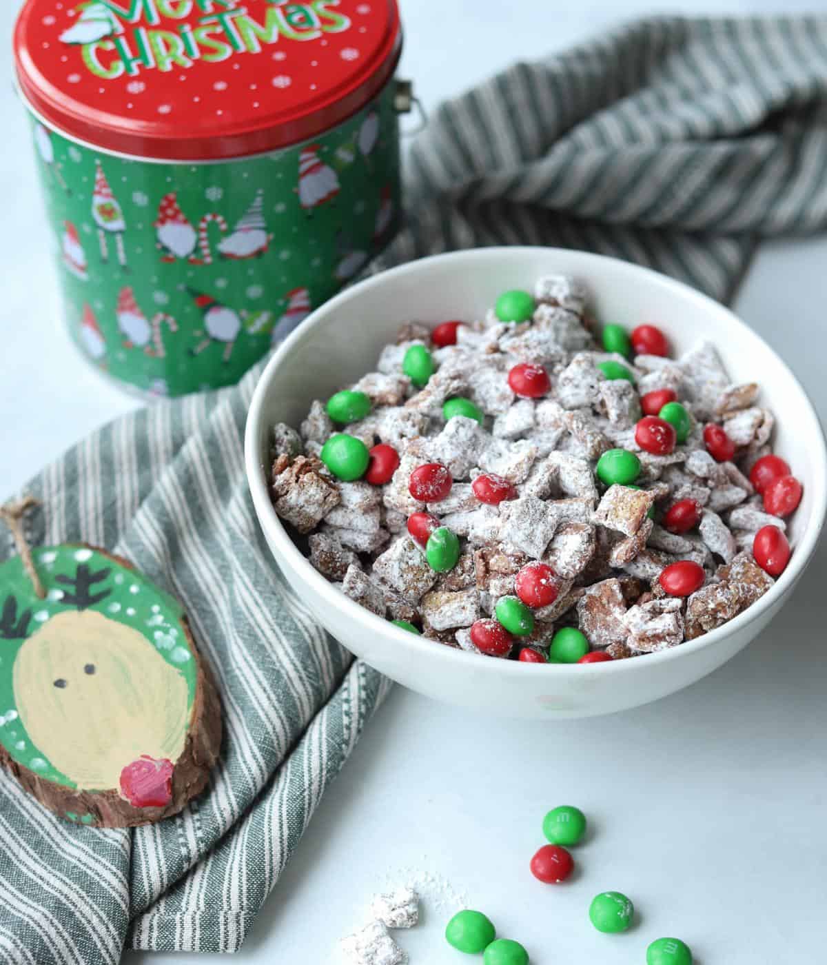 puppy chow in white bowl with a reindeer ornament and gnome tin on the side