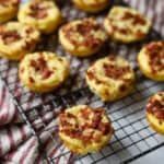 egg bites topped with bacon and melted cheese on a baking rack