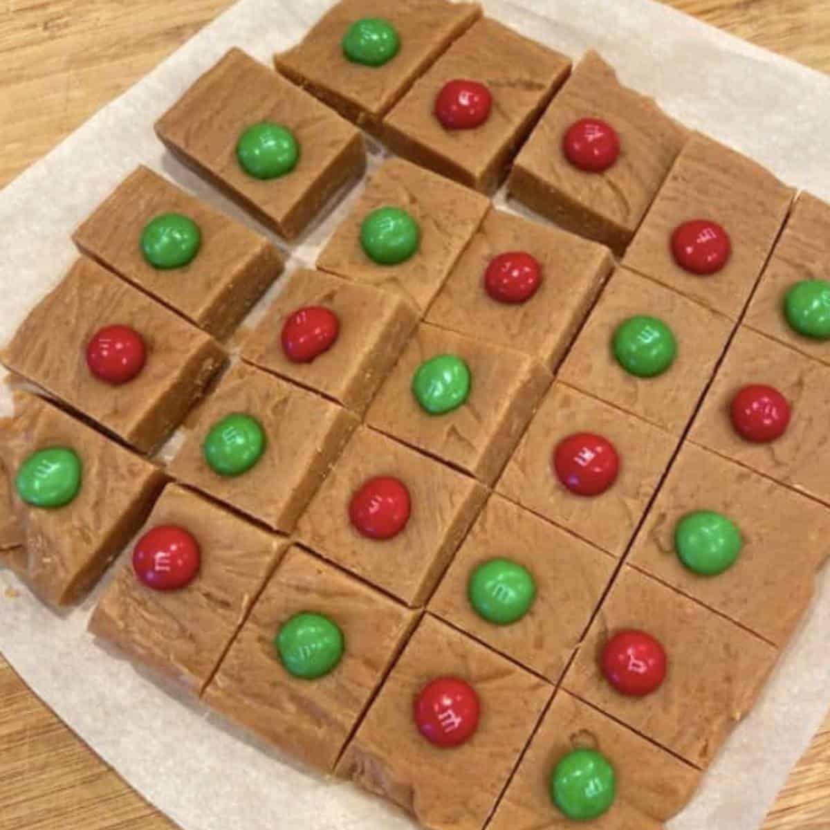 No bake peanut butter fudge cut into squares with christmas m&ms.