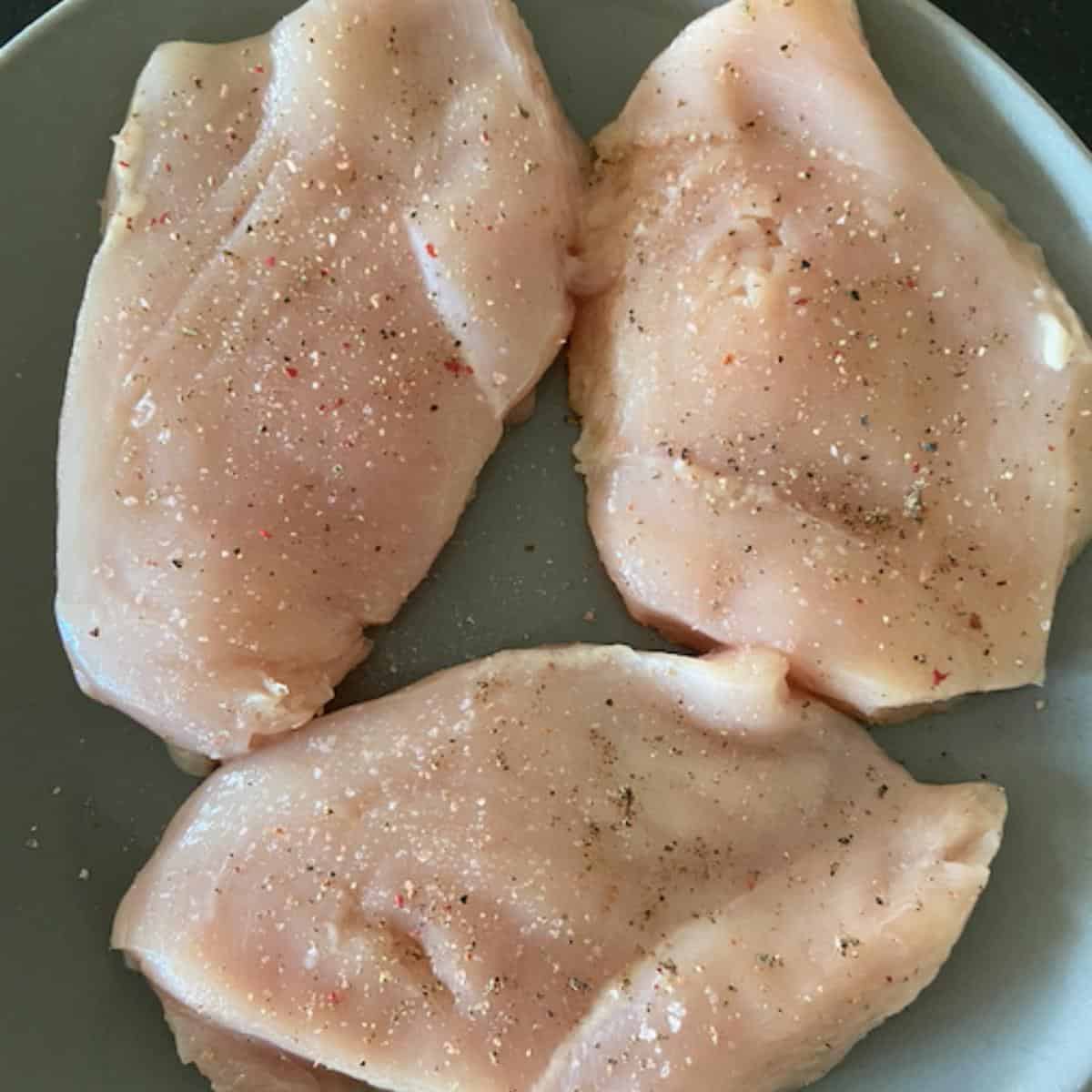 3 chicken breast on plate patted dry and seasoned with salt and pepper