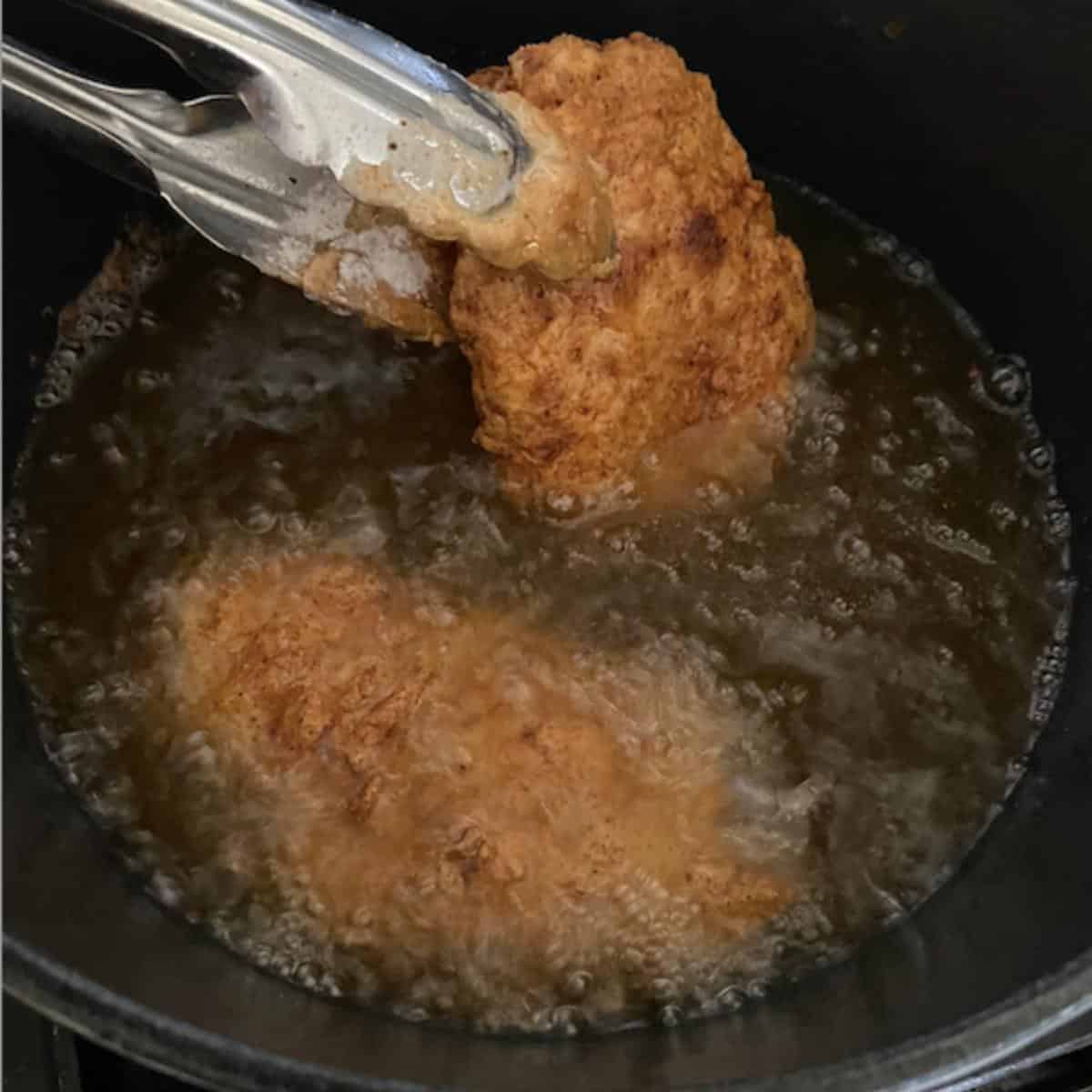 tong flipping fried chicken