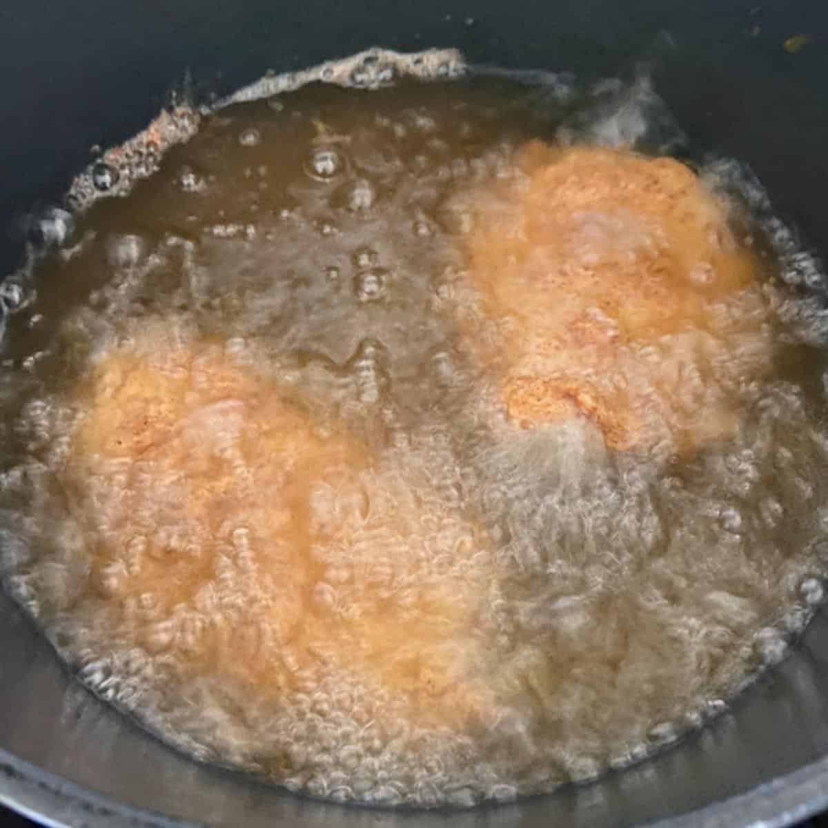 2 chicken breast frying in oil in the dutch oven