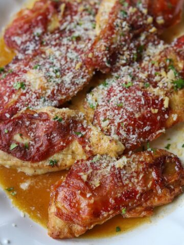 chicken prosciutto on serving plate topped with parmesan cheese