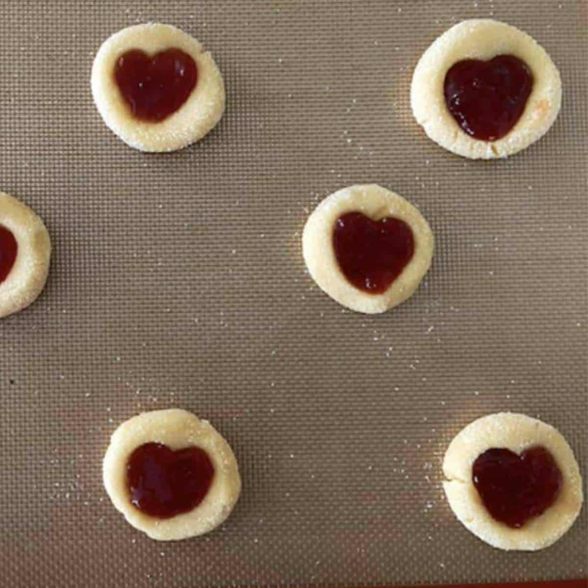 Heart jam cookies ready to bake on cookie sheet.