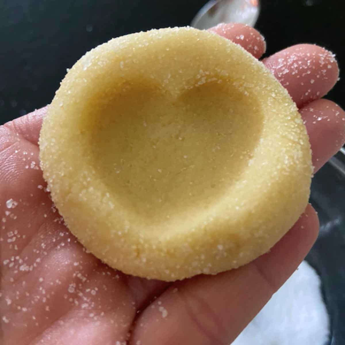 hand holding cookie with thumbprint imprint