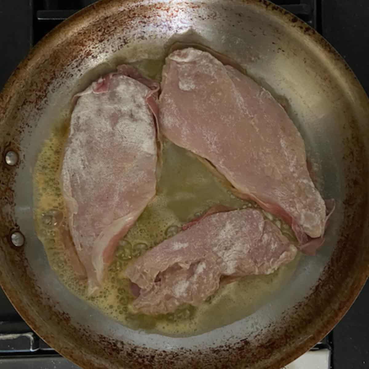 Chicken cooking in skillet prosciutto side down.