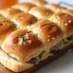 Hot Baked Roast beef sliders with horseradish sauce topped with garlic butter.