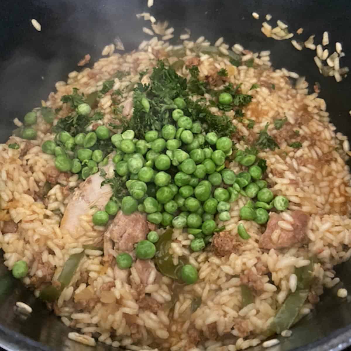 parsley and peas added into paella