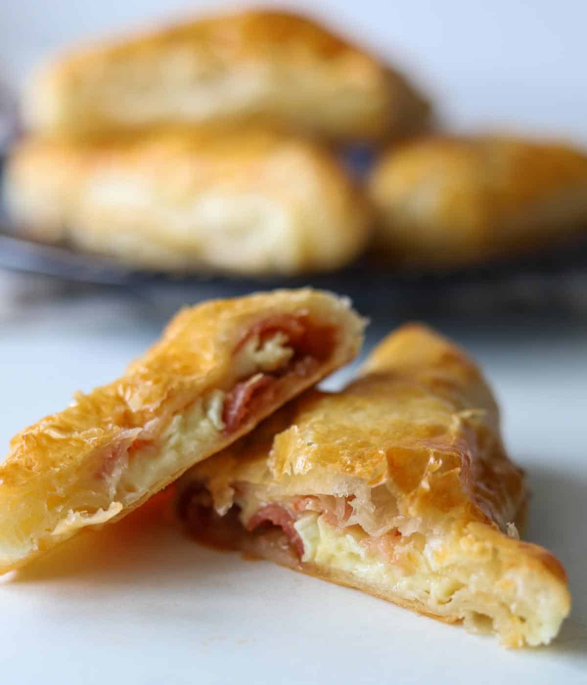 bacon and cheese turnover sliced in half with turnovers in background