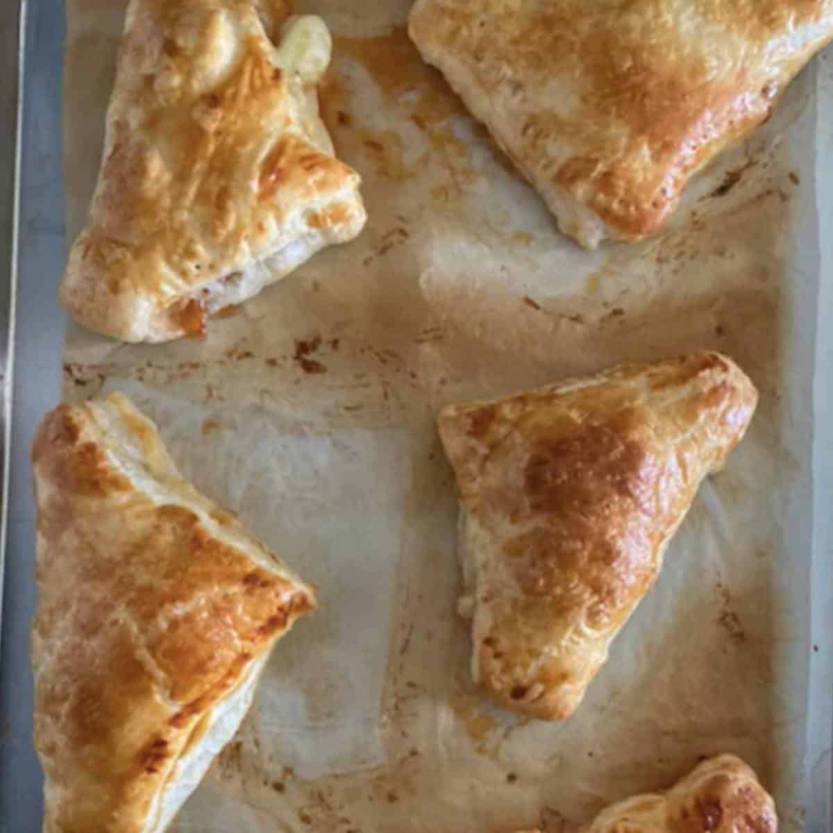 Baked bacon cheese turnovers on cookie sheet.