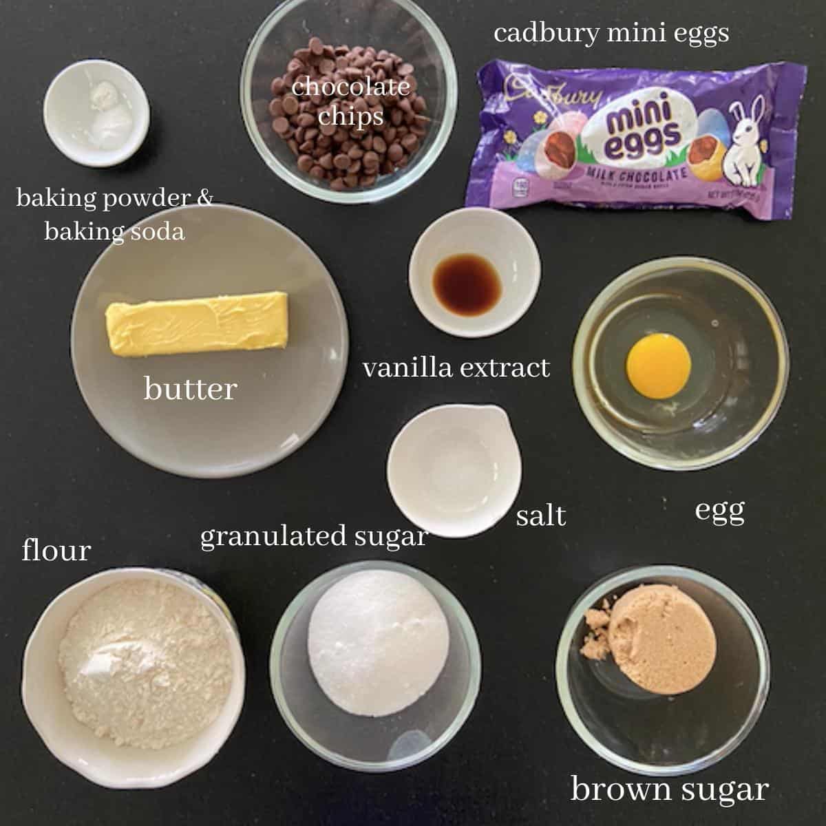 cadbury mini egg chocolate chip cookie ingredients on black countertop with text