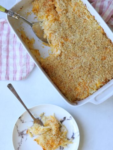 casserole dish full of hash brown casserole and small plate with a serving